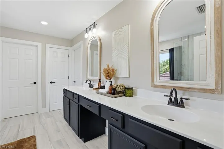 Dual vanity with dark cabinetry, white countertops, and matte black fixtures