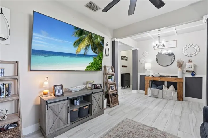 Spacious living area featuring light wood-finish flooring, a contemporary ceiling fan, and a built-in media console with barn door style cabinetry