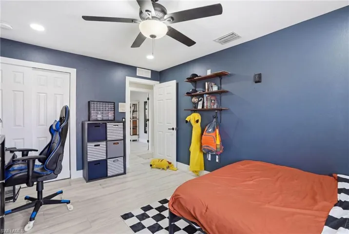 Room featuring blue accent wall, light wood-finish flooring, and white ceiling with a ceiling fan