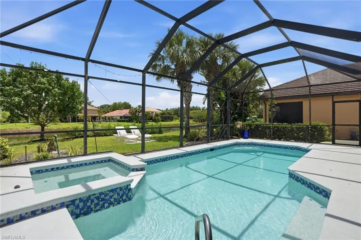 Screened enclosure featuring a rectangular pool with integrated spa, concrete decking, and mosaic tile accents