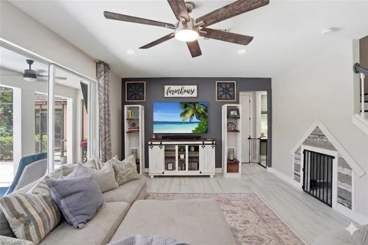 Living area featuring light wood-finish flooring, a ceiling fan with integrated lighting, and recessed lighting