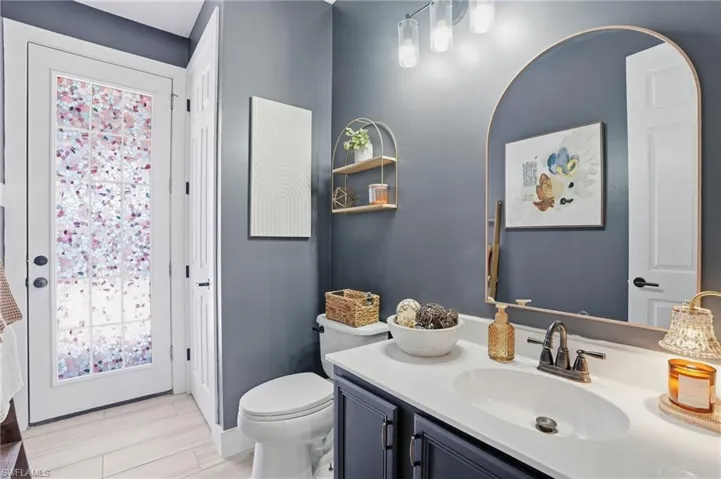 Bathroom vanity with integrated sink, bronze faucet, and arched mirror