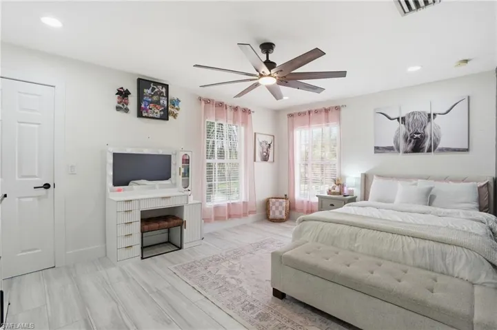 Recessed lighting, wood-finish flooring, a contemporary ceiling fan, and multiple windows provide a bright and airy atmosphere