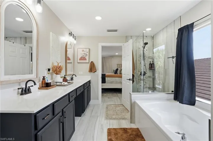 Spacious bathroom featuring a double vanity with dark cabinetry, white countertops, and black hardware
