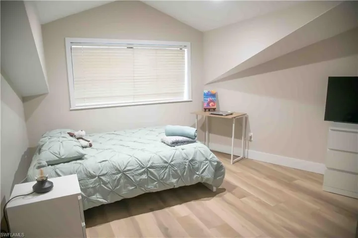 Bedroom with wood finished floors and lofted ceiling