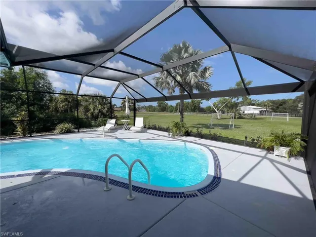 Outdoor pool with a patio area and glass enclosure