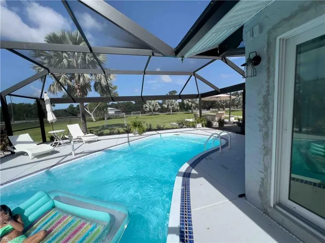 Swimming pool featuring a patio, glass enclosure, and a lawn