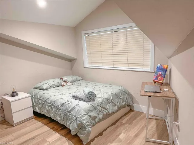 Bedroom with vaulted ceiling and light wood-style floors