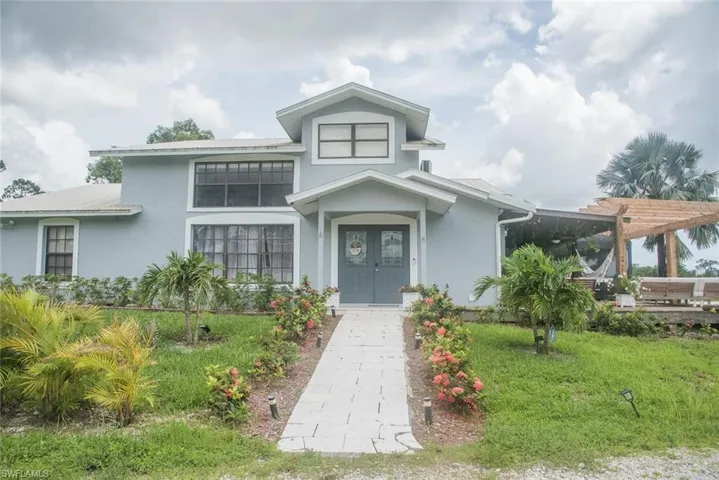 View of front of home featuring a pergola, stucco siding, and a front lawn