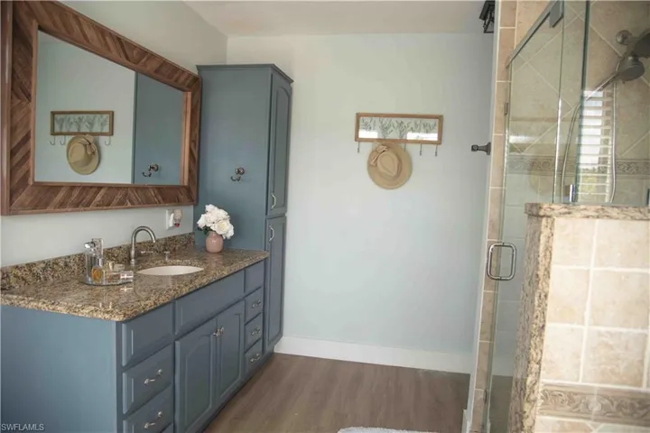 Bathroom featuring wood finished floors, vanity, and a shower stall