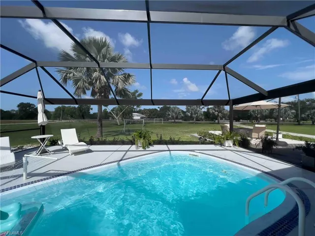 Swimming pool with a lawn, a patio, and glass enclosure