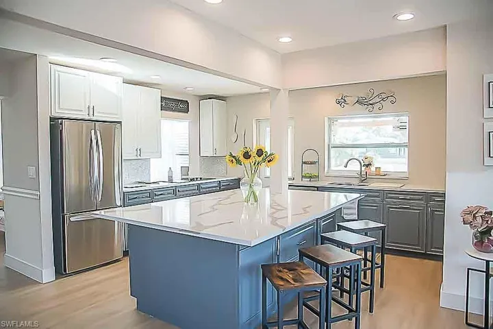 Kitchen featuring a kitchen bar, freestanding refrigerator, a kitchen island, white cabinetry, and light wood-type flooring