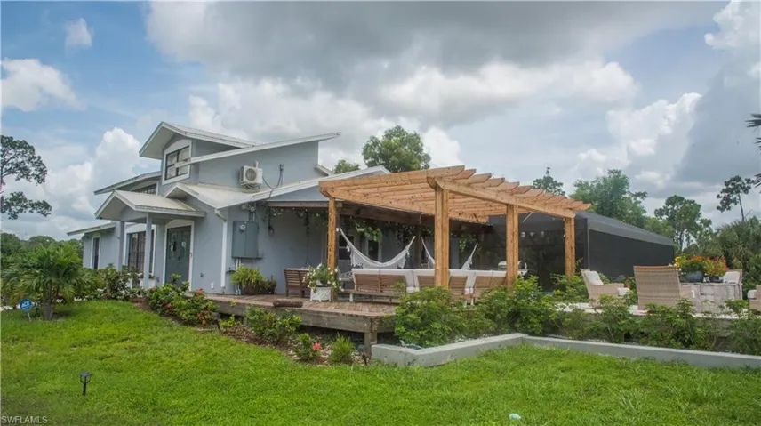 Rear view of house featuring a pergola, a yard, stucco siding, and a deck