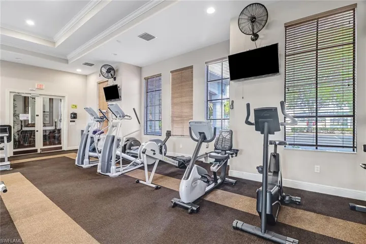 Dedicated fitness space featuring multiple exercise machines, recessed lighting, and wall-mounted televisions