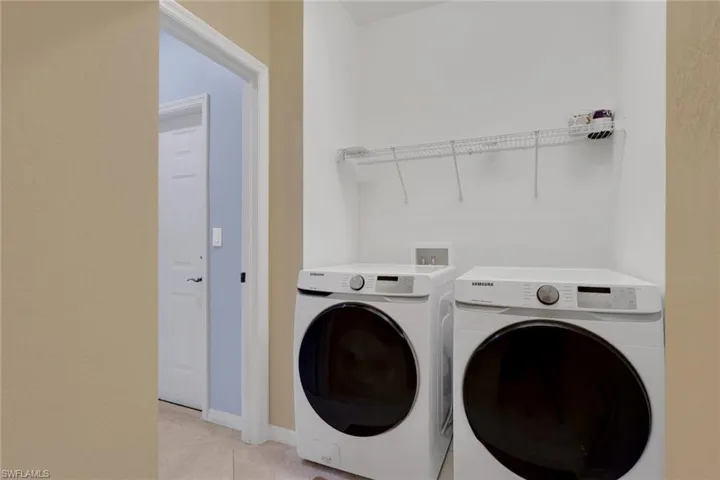 Dedicated laundry area featuring a wire storage shelf and light-colored tile flooring