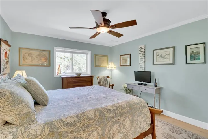 Bedroom with crown molding, light wood finished floors, and a ceiling fan
