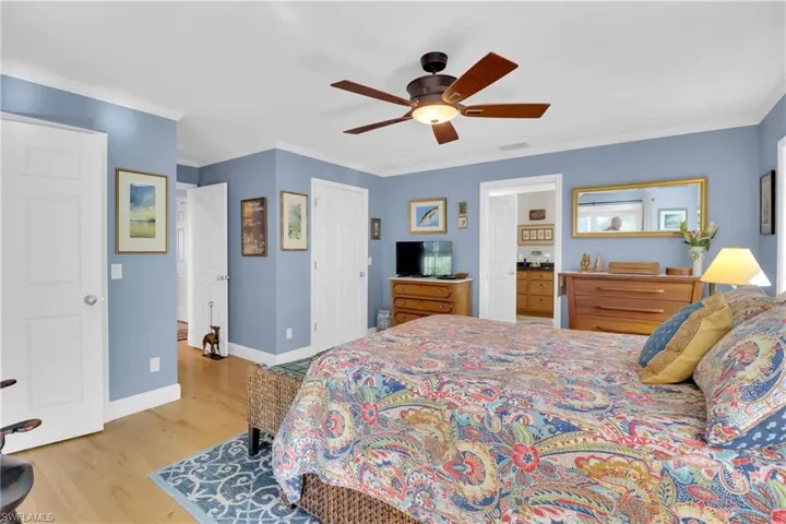 Bedroom with light wood-type flooring, ornamental molding, a ceiling fan, and a closet