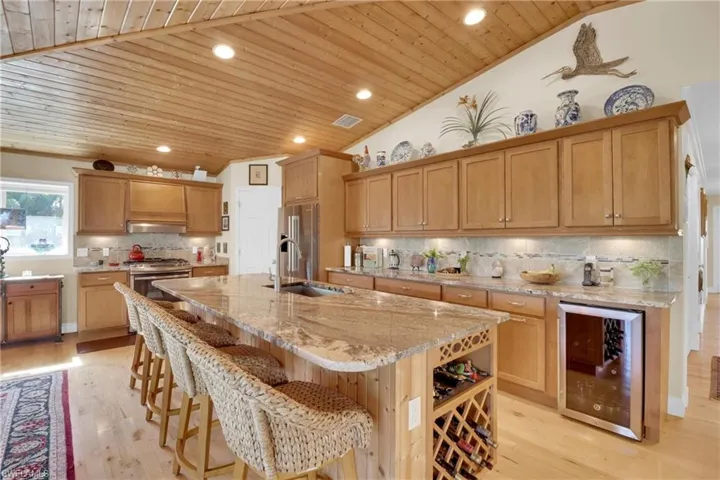 Kitchen featuring tasteful backsplash, vaulted ceiling, wood ceiling, wine cooler, and recessed lighting