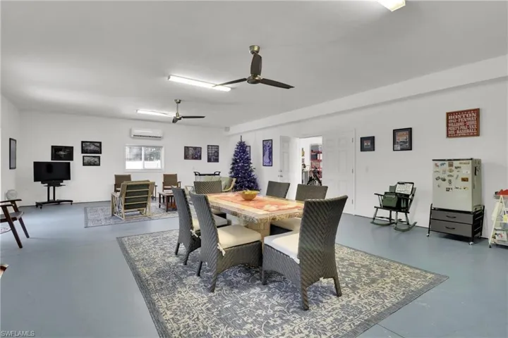 Great Roomwith finished concrete flooring, a ceiling fan, and a wall unit AC