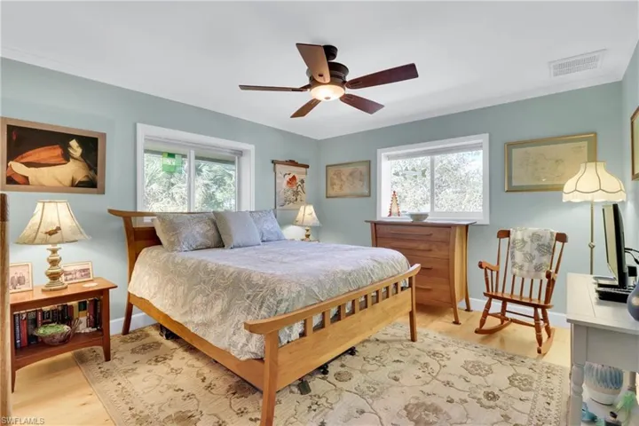 Bedroom with multiple windows, light wood finished floors, a ceiling fan, and crown molding