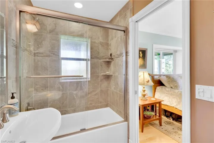 Bathroom featuring bath / shower combo with glass door and ensuite bath