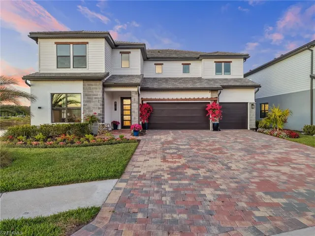 Prairie-style house with decorative driveway, a yard, a garage, and stone siding