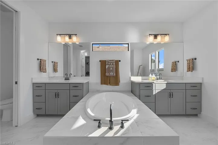 Full bathroom featuring two vanities and a garden tub