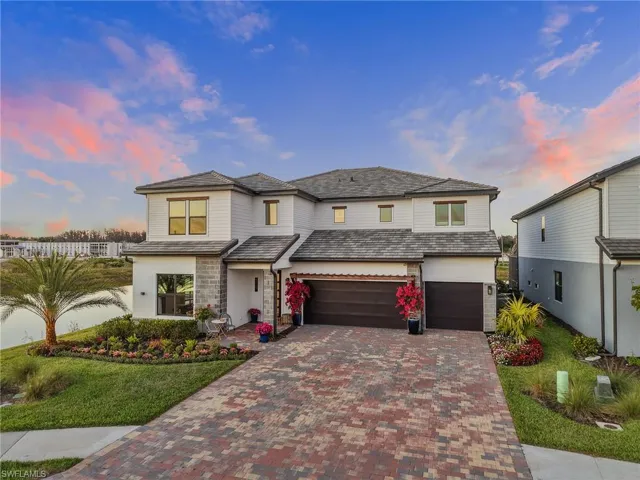 View of front of house featuring decorative driveway, an attached garage, a front yard, and stucco siding