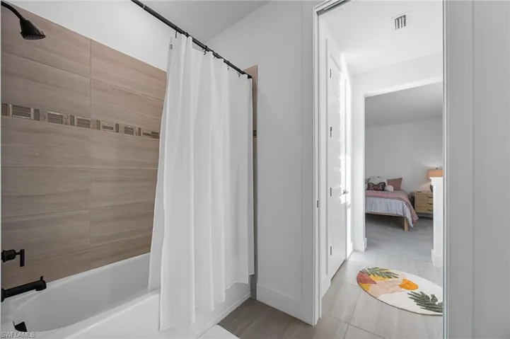 Ensuite bathroom featuring shower / bath combo with shower curtain and baseboards