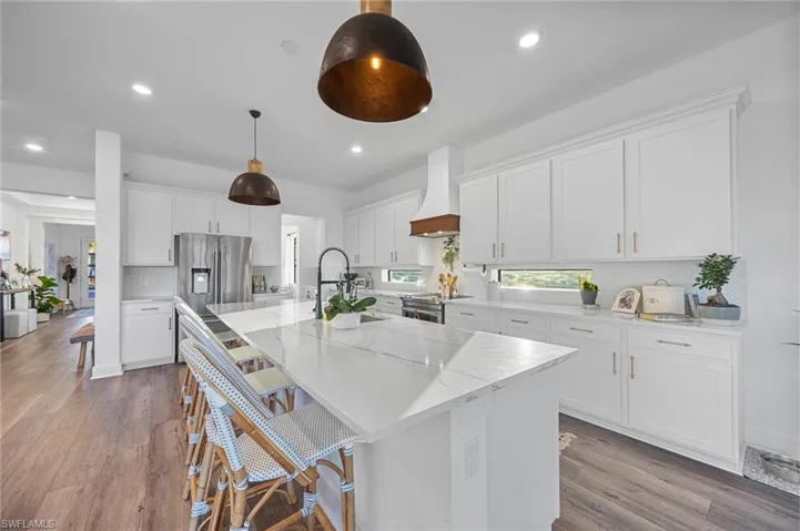 Kitchen featuring a kitchen bar, white cabinetry, and dark wood-style flooring