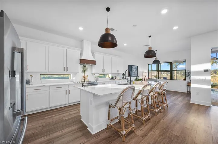 Kitchen featuring high end fridge, a center island with sink, a breakfast bar, and white cabinetry