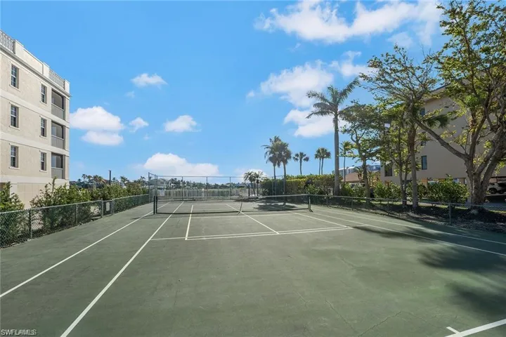 Full-size tennis court with a green surface and white line markings