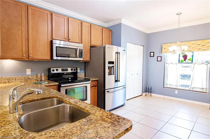 View from entry left of granite breakfast counter and attractive, efficient kitchen with stainless appliance package