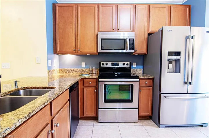 View from entry left of granite breakfast counter and attractive, efficient kitchen with stainless appliance package