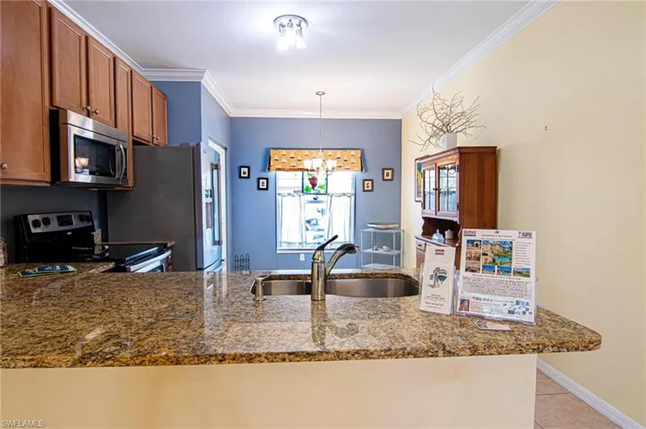 View from entry left of granite breakfast counter and attractive, efficient kitchen with stainless appliance package
