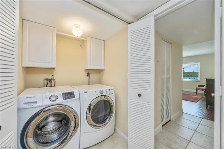 Washroom with cabinet space, independent washer and dryer, and light tile patterned floors