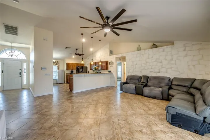 Living room featuring ceiling fan, a chandelier, and high vaulted ceiling