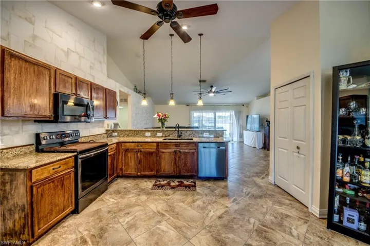 Kitchen featuring stainless steel appliances, a ceiling fan, a sink, a peninsula, and high vaulted ceiling