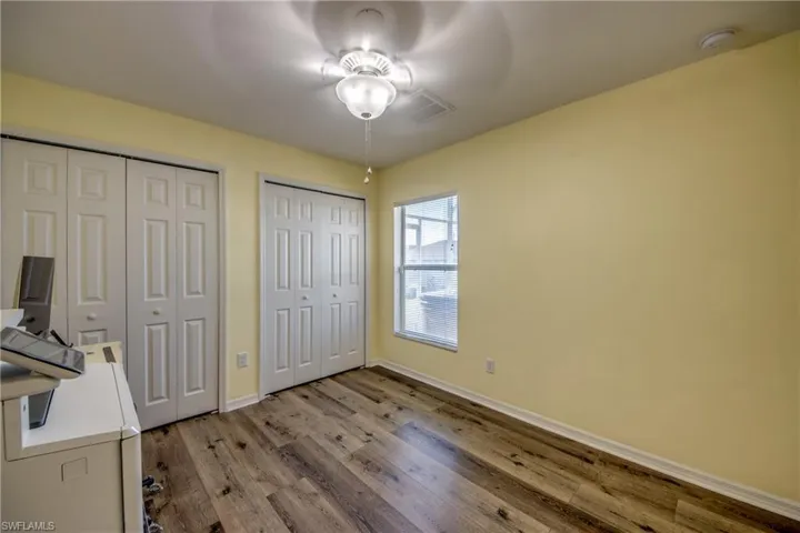 Unfurnished office featuring a ceiling fan, wood finished floors, and baseboards