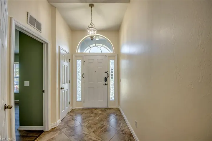 Foyer with baseboards and a chandelier