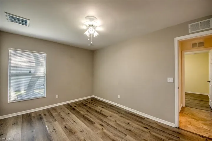 Empty room with a ceiling fan, wood finished floors, and baseboards