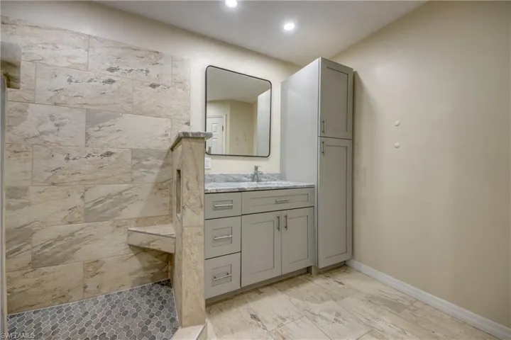 Full bath with tiled shower, vanity, recessed lighting, baseboards, and marble finish flooring