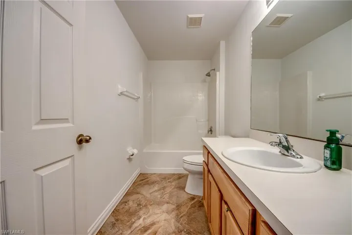 Full bath featuring toilet, vanity, bathing tub / shower combination, and baseboards