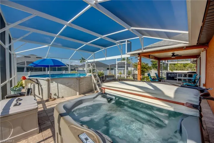 Outdoor pool with a hot tub, a patio area, glass enclosure, and a ceiling fan