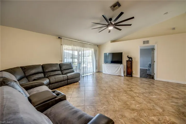 Living room with ceiling fan, lofted ceiling, and baseboards