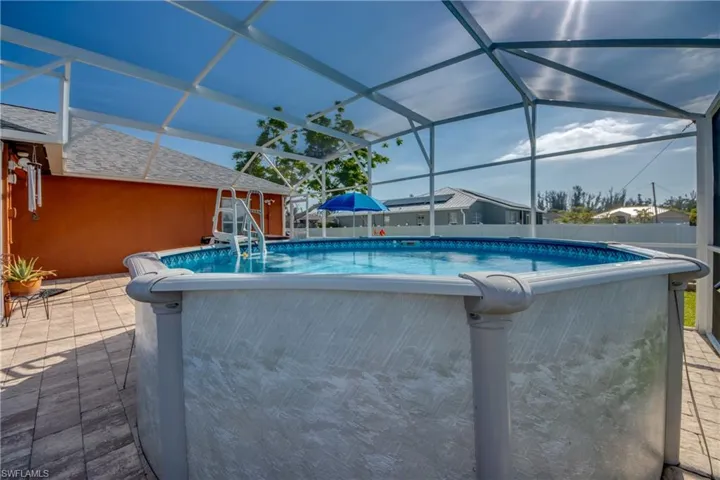 View of swimming pool featuring glass enclosure and a patio