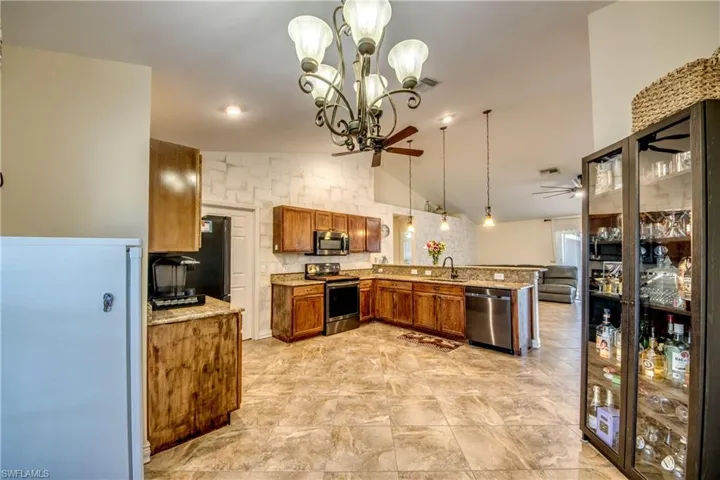 Kitchen featuring stainless steel appliances, a sink, a peninsula, a ceiling fan, and brown cabinetry