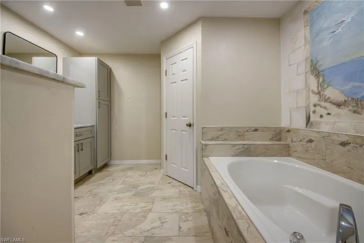 Full bathroom featuring a garden tub, recessed lighting, and vanity