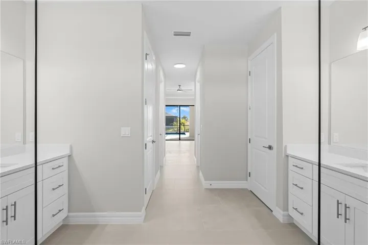 Bathroom featuring two vanities, light tile patterned flooring, and ceiling fan