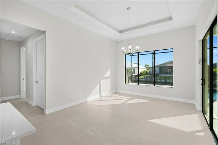 Unfurnished dining area with a raised ceiling, a chandelier, and concrete floors
